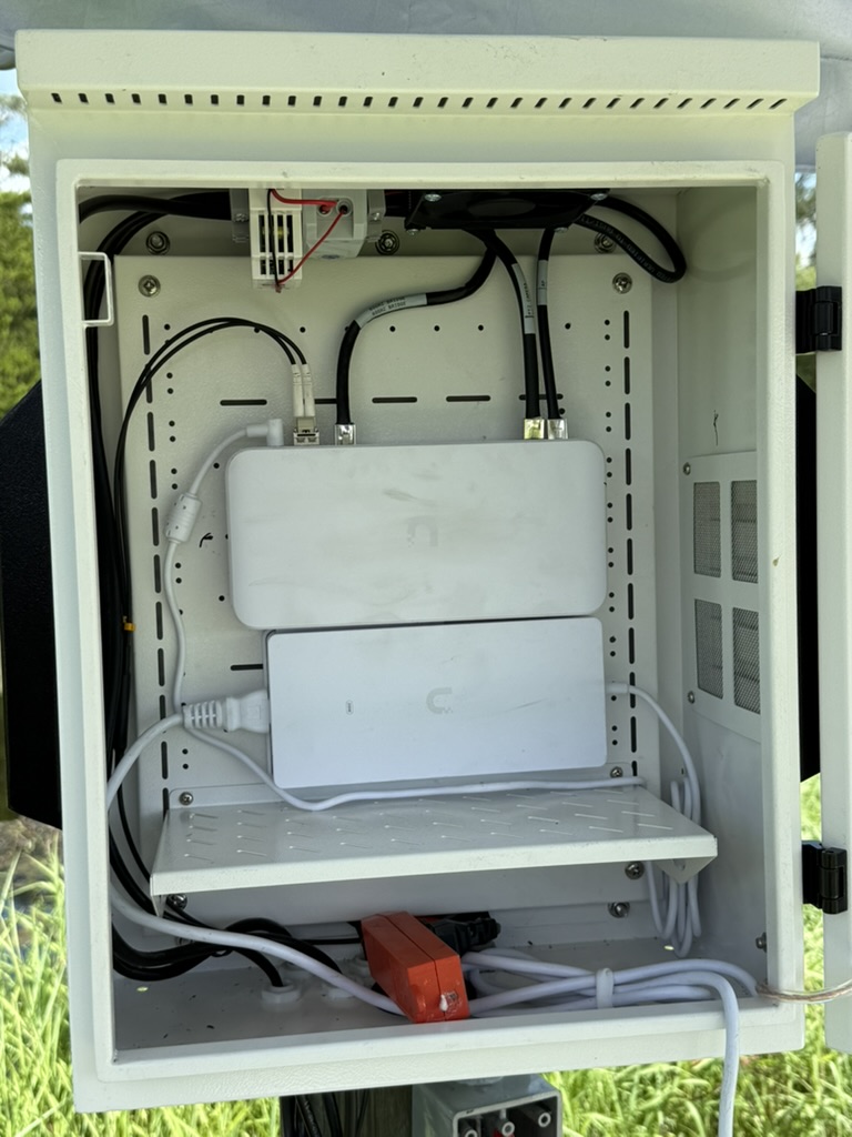 Inside view of an outdoor cabinet with network equipment and cable management.