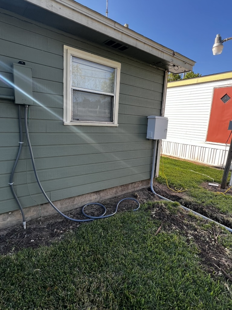 Gray conduit and a service loop routed to an exterior building wall.