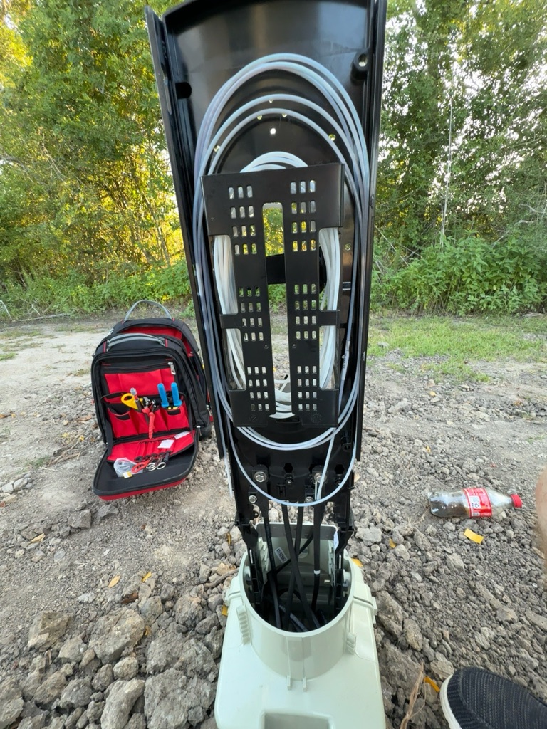Open fiber distribution cabinet with neatly routed fiber cable and field tools nearby.