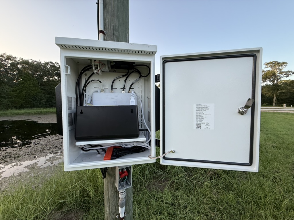 Open outdoor pole cabinet with network equipment and cable routing.
